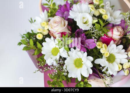 Un beau bouquet de fleurs fraîches aux couleurs pastel, y compris des roses, des marguerites et des alstroemerias, disposés dans un panier Banque D'Images