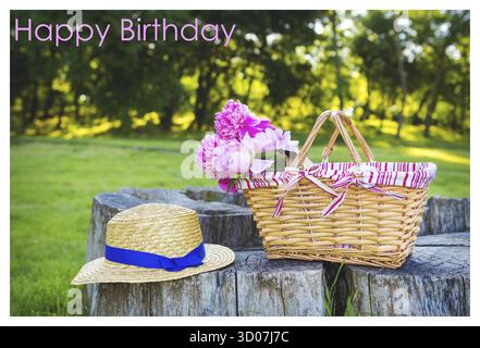 Magnifique chapeau de paille et fleurs dans un stand de panier sur une inscription d'anniversaire en bois heureux Banque D'Images