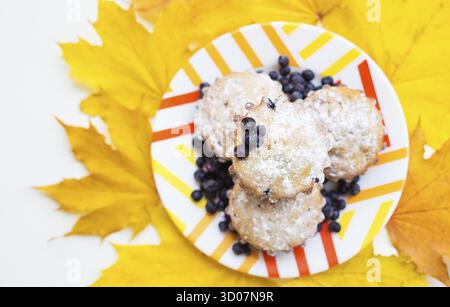 Muffins aux bleuets sur plaque et feuillage d'automne jaune vif Banque D'Images