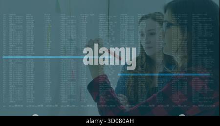 Deux femmes collaborant dans la salle de réunion de bureau, annotant le code et les journaux sur panneau de verre avec tablette Banque D'Images