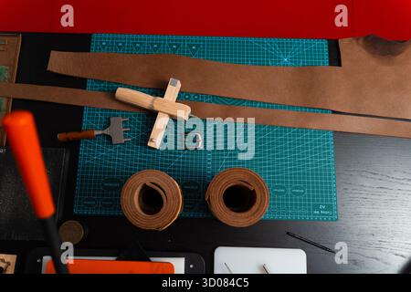 Installation de travail du cuir avec des outils, une boucle et des bandes de cuir disposées soigneusement sur un tapis, prêt pour la fabrication de ceinture. Outils de maroquinerie et fabrication de courroies p Banque D'Images