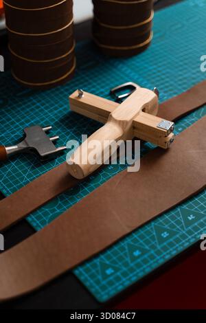 Installation de travail du cuir avec des outils, une boucle et des bandes de cuir disposées soigneusement sur un tapis, prêt pour la fabrication de ceinture. Outils de maroquinerie et fabrication de courroies p Banque D'Images