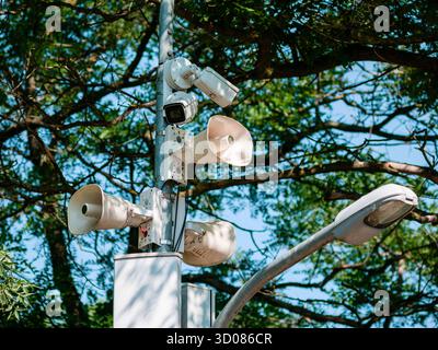 Caméras de surveillance et haut-parleurs de sonorisation installés sur un lampadaire de parc, surveillance et diffusion en plein air Banque D'Images