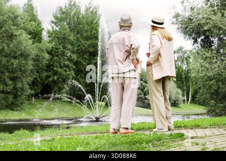 Deux femmes âgées debout sur toute la longueur dans le parc ensemble, admirant un beau paysage naturel et appréciant un mode de vie actif, l'amitié et le pois Banque D'Images