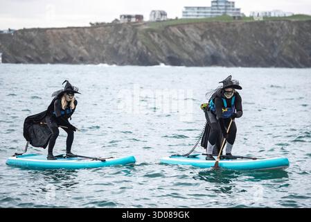 DATE DE CORRECTION RETRANSMISE les paddleboarders du Newquay Activity Centre entrent dans l'esprit d'Halloween lors d'une pagaie tôt le matin à l'aube à travers Newquay Bay à Cornwall, où les amateurs de sports nautiques préparent des tenues pour une semaine de célébration des activités dans la ville balnéaire pendant Spooky Newquay pendant les vacances d'Halloween, à partir du samedi 25 octobre. Date de la photo : mercredi 22 octobre 2025. Banque D'Images