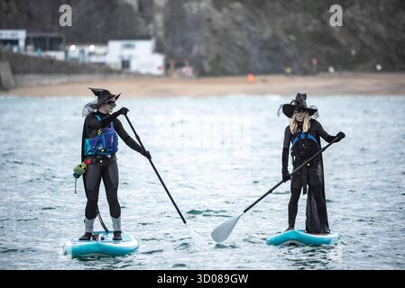 DATE DE CORRECTION RETRANSMISE les paddleboarders du Newquay Activity Centre entrent dans l'esprit d'Halloween lors d'une pagaie tôt le matin à l'aube à travers Newquay Bay à Cornwall, où les amateurs de sports nautiques préparent des tenues pour une semaine de célébration des activités dans la ville balnéaire pendant Spooky Newquay pendant les vacances d'Halloween, à partir du samedi 25 octobre. Date de la photo : mercredi 22 octobre 2025. Banque D'Images