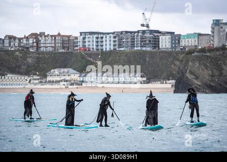 DATE DE CORRECTION RETRANSMISE les paddleboarders du Newquay Activity Centre entrent dans l'esprit d'Halloween lors d'une pagaie tôt le matin à l'aube à travers Newquay Bay à Cornwall, où les amateurs de sports nautiques préparent des tenues pour une semaine de célébration des activités dans la ville balnéaire pendant Spooky Newquay pendant les vacances d'Halloween, à partir du samedi 25 octobre. Date de la photo : mercredi 22 octobre 2025. Banque D'Images