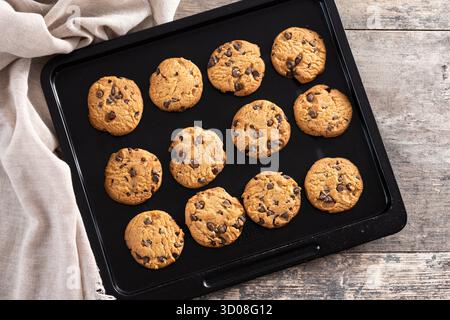 Gros plan de biscuits aux pépites de chocolat maison refroidissant sur une plaque de cuisson noire. Banque D'Images