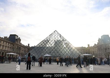 Paris, France. 22 octobre 2025. Les touristes sont photographiés devant la pyramide du Louvre à Paris, France, 22 octobre 2025. Le musée du Louvre a rouvert aux visiteurs mercredi matin, trois jours après un vol de bijoux qui a causé des pertes considérables. Crédit : Zhang Baihui/Xinhua/Alamy Live News Banque D'Images