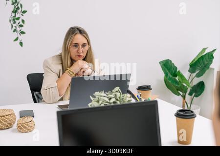 femme travaillant au bureau, concentrée sur son ordinateur Banque D'Images