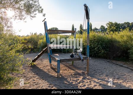 Terrain de jeu avec cadre d'escalade sur un terrain de gravier. Objet d'activité de loisirs vide dans un espace public en Allemagne. Bâtiment en bois adapté aux enfants. Banque D'Images