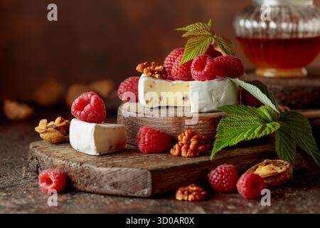 Camembert avec framboises fraîches et noix sur une table vintage brune. Banque D'Images