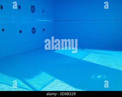 Vue sous-marine d'une piscine carrelée vide avec lumière du soleil et ombres Banque D'Images