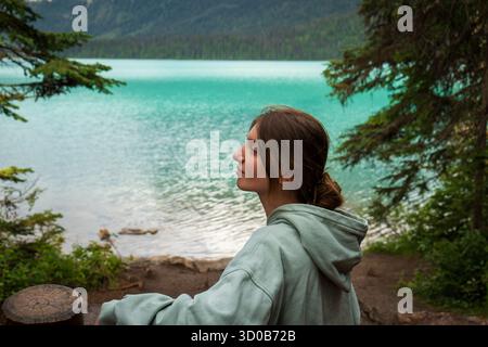 Femme profitant de la vue sereine d'un paysage de lac alpin turquoise vibrant. Emerald Lake, C.-B. Banque D'Images
