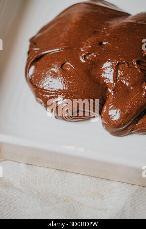 Un grand morceau de gâteau au chocolat est assis sur une assiette blanche. Le gâteau est recouvert de chocolat et il est très riche et décadent. Concept d'indulgence Banque D'Images