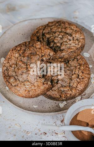 Trois muffins sont sur une assiette blanche avec un bol de cannelle et de sucre à côté. Les muffins sont bruns et semblent être fraîchement cuits Banque D'Images