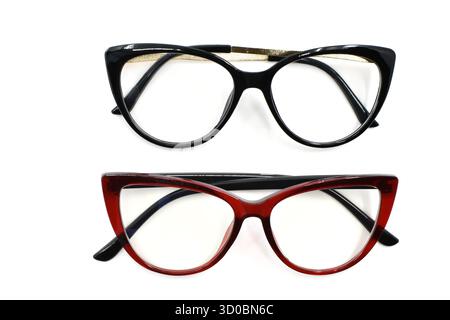 Deux paires de lunettes pour femmes avec des cadres en forme de cate Yee rouge et noir isolés sur un fond blanc Uni. Concept de vision et de vision. Banque D'Images