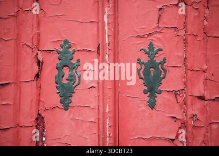 Plaques de verrouillage et peinture rouge fissurée et écaillée sur une vieille porte au Portugal Banque D'Images