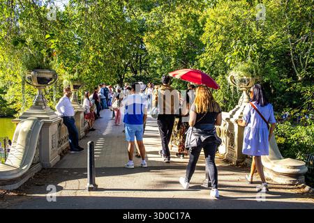 Les gens marchent sur le pont Bow au-dessus du lac dans Central Park par une journée d'été ensoleillée. Touristes appréciant le parc public de Manhattan, New York. Banque D'Images
