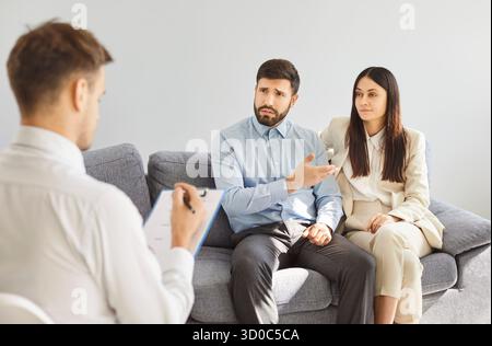 Couple parlant de problèmes de mariage assis au bureau de psychologue de famille pendant la séance de thérapie Banque D'Images