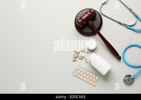 Juge marteau, pilules et stéthoscope sur fond gris. Concept de réforme des soins de santé Banque D'Images