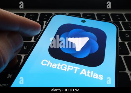 ChatGPT Atlas sur le téléphone dans la main au-dessus du clavier de l'ordinateur portable montre de nouvelles fonctionnalités de mode agent. Stafford, Royaume-Uni, 22 octobre 2025 Banque D'Images