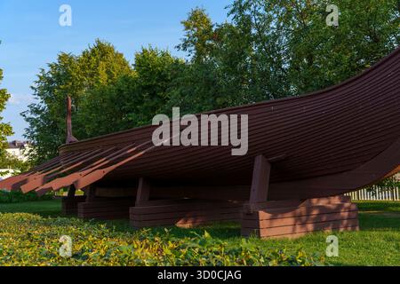 Grande réplique de bateau en bois de style viking avec des rames exposées dans un parc verdoyant à Vyborg, en Russie, entouré d'arbres par une journée ensoleillée Banque D'Images
