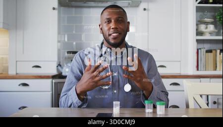 Médecin gestuel parlant dans la cuisine avec stéthoscope, échantillons de pots avec couvercles verts blancs et tablette Banque D'Images