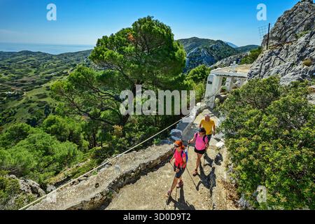 Trois personnes randonnée dans une forêt de pins grecs, ancienne chapelle en arrière-plan, Katounes, Skyros, mer Égée, Sporades, Grèce centrale, Grèce Banque D'Images