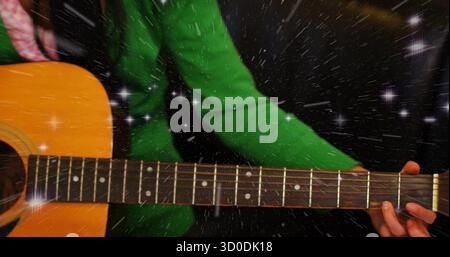 Femme strumming portant un pull vert vif à la maison, avec guitare acoustique et superposition Starburst Banque D'Images