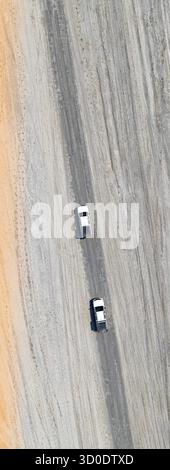 Vue aérienne, vue de haut en bas, deux voitures hors route conduisant sur une route dans la campagne aride, Botswana Banque D'Images