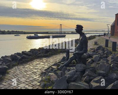 Photo avec une ambiance mélancolique de sculpture en bronze Poortekerl regardant le Rhin en attente du navire à décharger, navigation rhénane navigation intérieure, réminiscence Banque D'Images