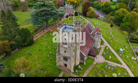 Vue aérienne de l'église Sainte-Marie debout au milieu d'une mer d'herbe verte et de pierres tombales, sa pierre altérée contrastant avec le toit de tuiles rouges, Leigh, Angleterre, Royaume-Uni. Banque D'Images