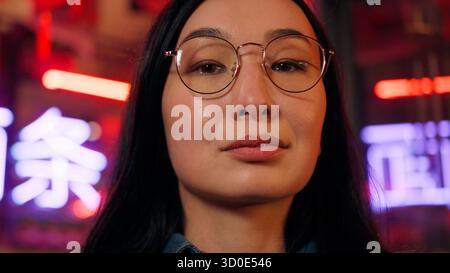 Réussie femme d'affaires asiatique confiante fille japonaise femme d'affaires femme d'affaires femme regardant caméra mis sur des lunettes de vue vision ville néon lumières. Le Banque D'Images