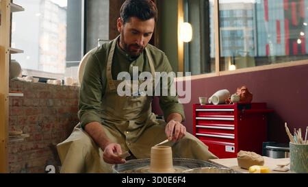 Concentré talentueux homme caucasien heureux gars masculin dans le tablier petite entreprise créant maître propriétaire artiste artisan potier faisant à la main sculpt filature Banque D'Images
