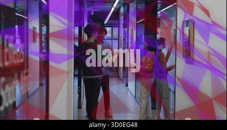 Collègues en chandails discutant du projet dans le couloir en verre, tenant la tablette, le dossier jaune, les papiers Banque D'Images