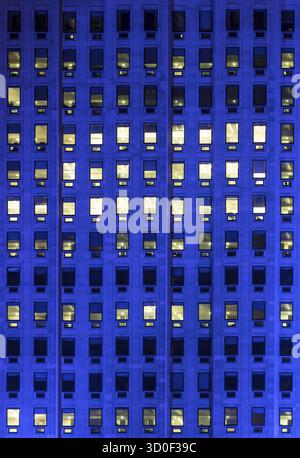 Lumière bleue extérieure sur les fenêtres d'un immeuble de bureaux de haute hauteur Banque D'Images