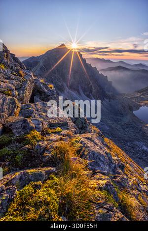 Vue aérienne de la lumière dorée du soleil éclatant sur les sommets accidentés d'Ostra, projetant de longues ombres à travers le paysage alpin, Vysoke Tatry, Presovsky kraj, Slovaquie. Banque D'Images