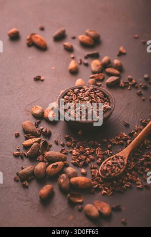 Graines de cacao bio et fèves de cacao dans un bol sur fond brun Banque D'Images