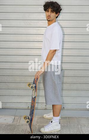 Skateur urbain en vêtements athlétiques regardant la caméra Banque D'Images