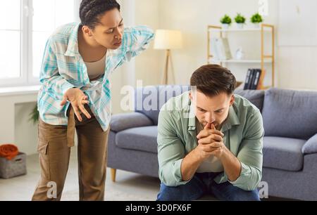 Femme afro-américaine en colère criant sur l'homme frustré bouleversé dans le salon à la maison. Banque D'Images