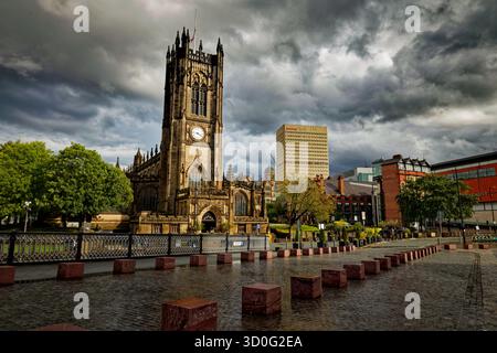 Une vue de l'autre côté d'un Wet Exchange Square jusqu'à la cathédrale de Manchester alors que les nuages de tempête se brisent, avec l'horizon du centre-ville au-delà, Manchester, Angleterre. Banque D'Images