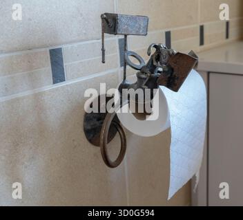 Support de papier toilette comprenant une souris de dessin animé en métal assise lisant le journal tout en étant assise sur ses toilettes avec un réservoir au-dessus de lui. Banque D'Images