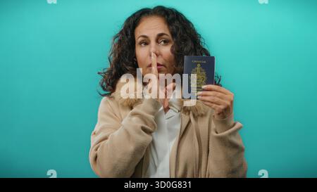 Femme détenant un passeport canadien sur fond bleu affichant des traits et une expression d'âge moyen. Banque D'Images
