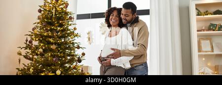 Un couple joyeux partage un moment tendre alors qu’ils se préparent à leur nouvelle arrivée à la maison, bannière Banque D'Images