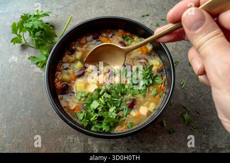 Soupe de haricots rouges avec pommes de terre, tomates, paprika, carotte et bacon sur une table en pierre. Vue de dessus. Copier l'espace. Banque D'Images