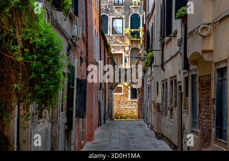 Un passage étroit avec un bâtiment éclairé par la lumière du soleil dans le sestiere San Polo de Venise, Italie Banque D'Images