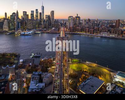Vue aérienne de l'emblématique pont de Brooklyn illuminé d'une série de lumières, reliant à l'horizon animé de Manhattan sous le crépuscule s'estompant, Manhattan, New York, États-Unis. Banque D'Images