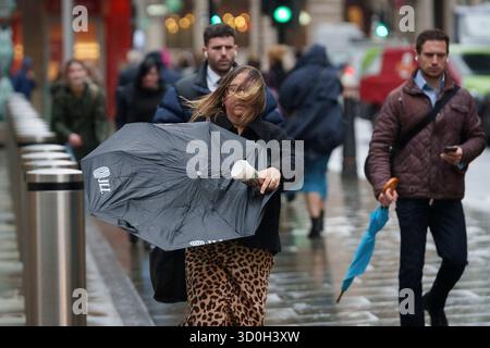 Les Londoniens négocient des vents forts de la tempête Benjamin dans la ville de Londres, le quartier financier de la capitale, le 23 octobre 2025, à Londres, en Angleterre. Benjamin a causé des pannes de courant dans l'est de l'Angleterre après que le met Office a émis un avertissement météorologique, estimant la vitesse du vent jusqu'à 70 mph (113 km/h). Banque D'Images