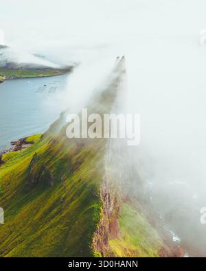 Vue aérienne de la spectaculaire pile de la mer de Drangarnir perçant à travers le voile brumeux, où les falaises vertes rencontrent l'océan bleu, Drangarnir, îles Féroé. Banque D'Images